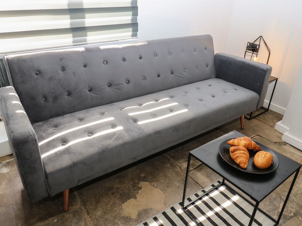 A living room with a sofa and a table holding croissants at Myrtle Nook in Keighley