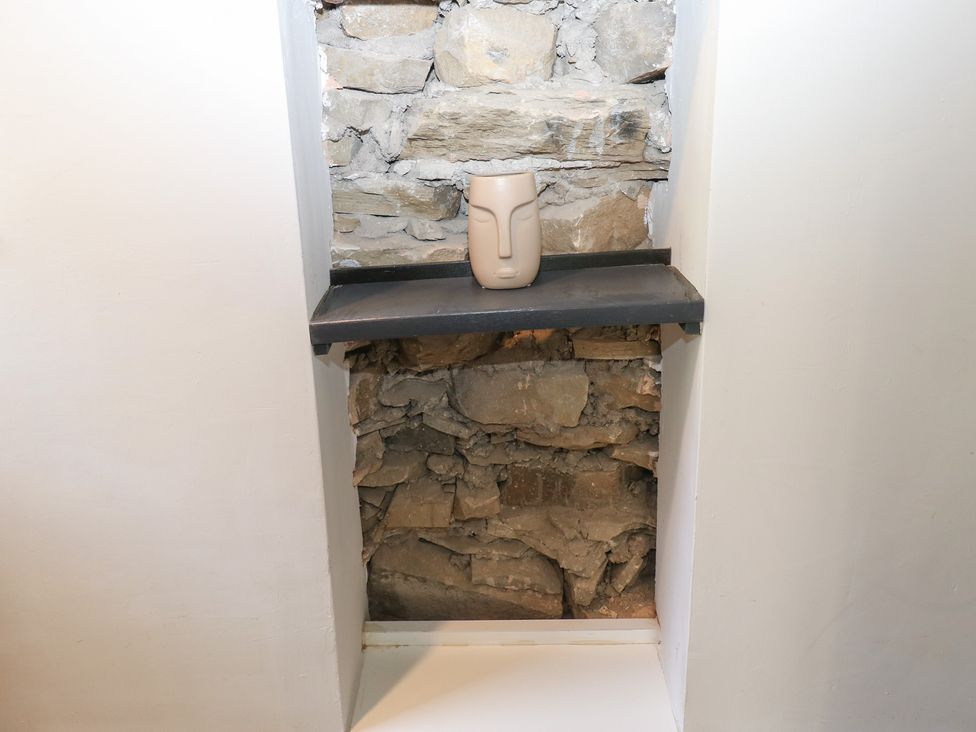 A shelf with a vase against a stone wall at Myrtle Nook in Keighley