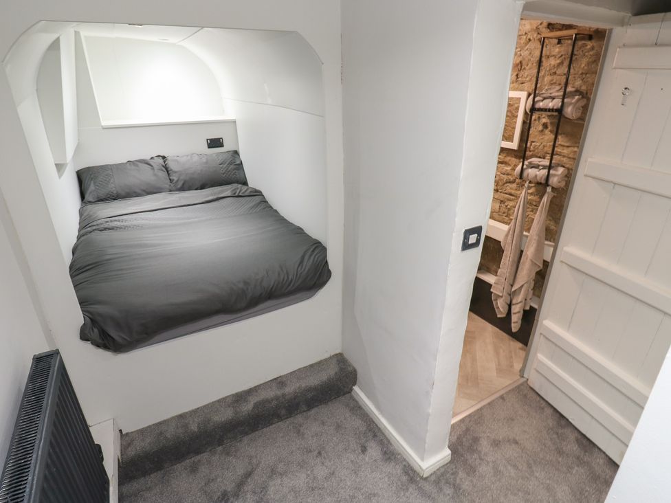 A bedroom with a bed and towels hanging in the corner at Myrtle Nook in Keighley