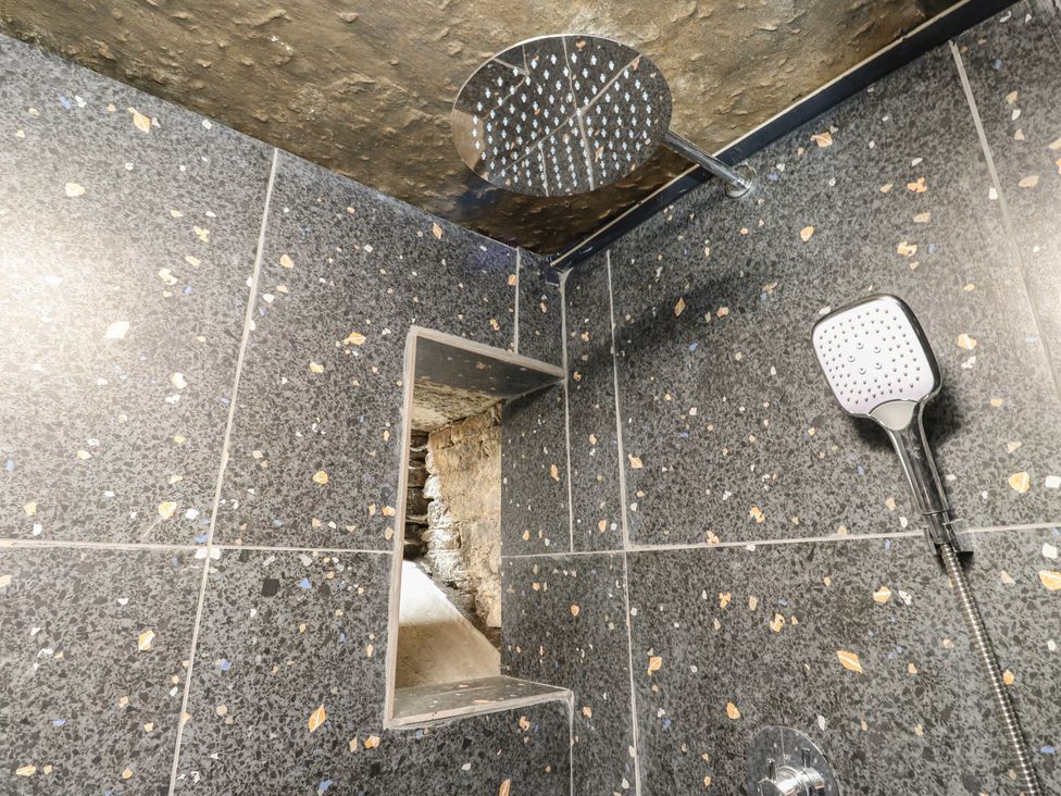 A shower with tile walls and a shower head at Myrtle Nook in Keighley