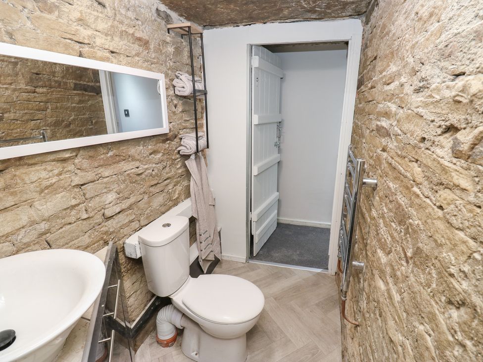 A bathroom with sink, toilet, mirror, and towel rack at Myrtle Nook in Keighley