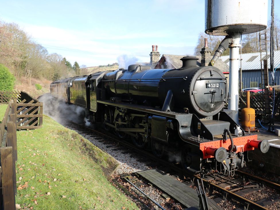 A steam locomotive next to a water tower at Myrtle Nook in Keighley