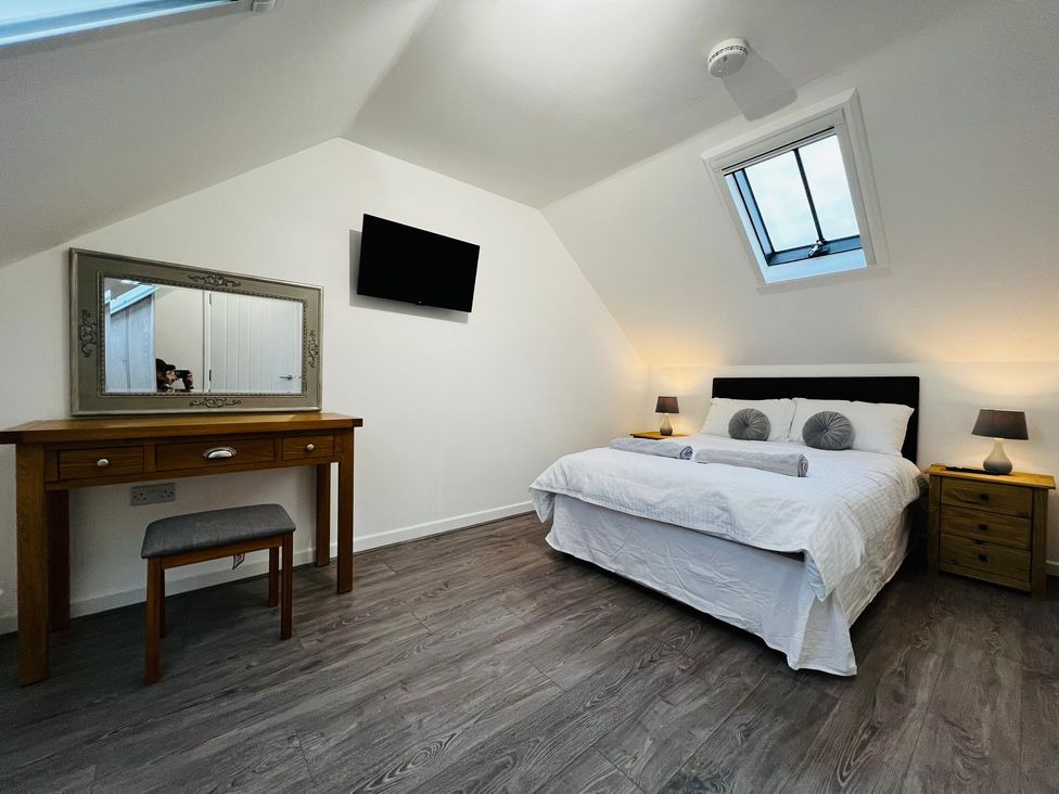 A bedroom with a bed and a mirror at Barn Cottage in Frome