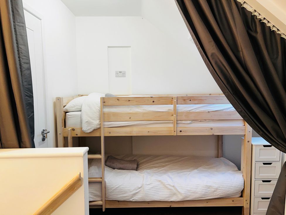 A bedroom with a bunk bed and a curtain at Barn Cottage Frome