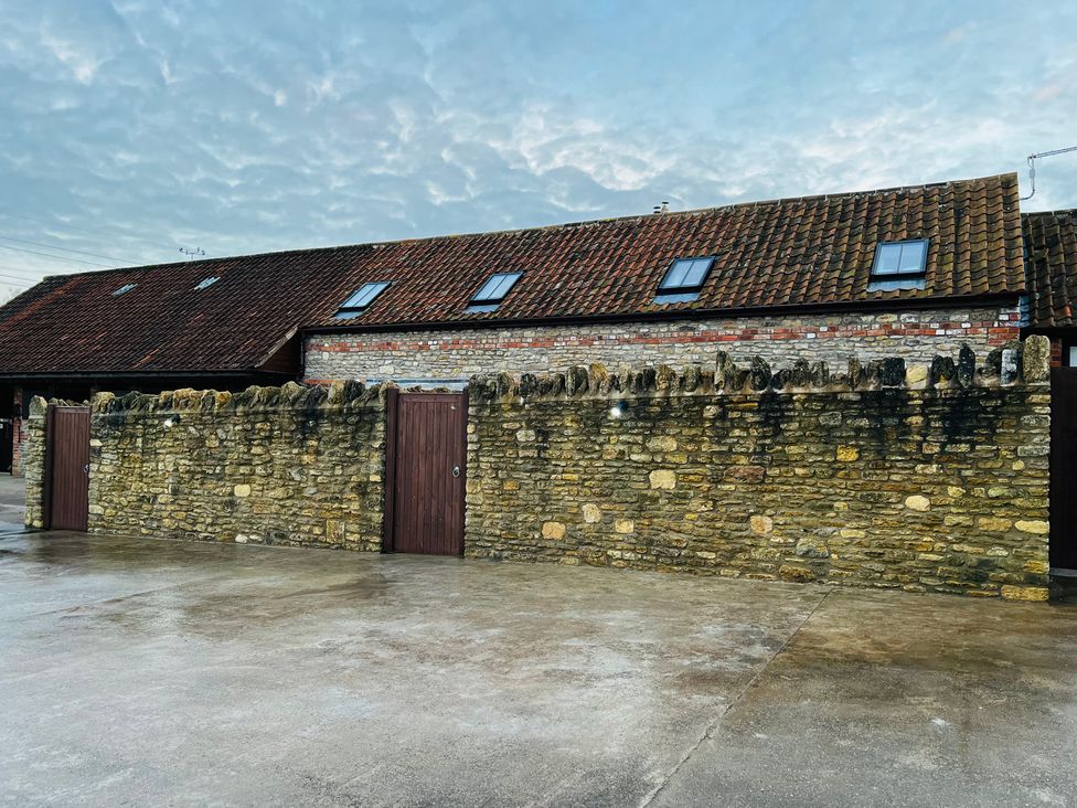 An outdoor area with a stone wall and a brick building at Barn Cottage in Frome