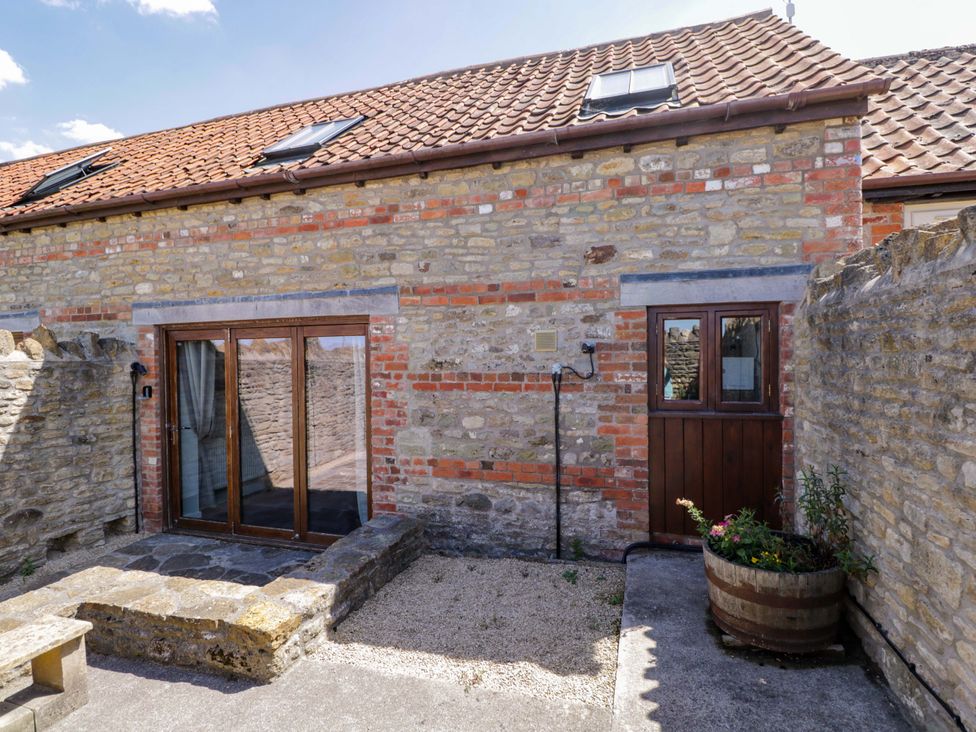 An outdoor area with a stone wall and wooden doors at Barn Cottage in Frome