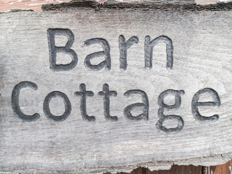 A wooden sign with the words Barn Cottage at Barn Cottage in Frome