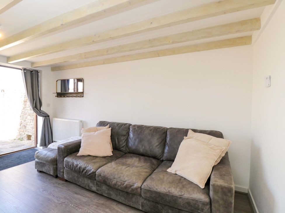 A living room with a sofa and a door to the outside at Barn Cottage in Frome