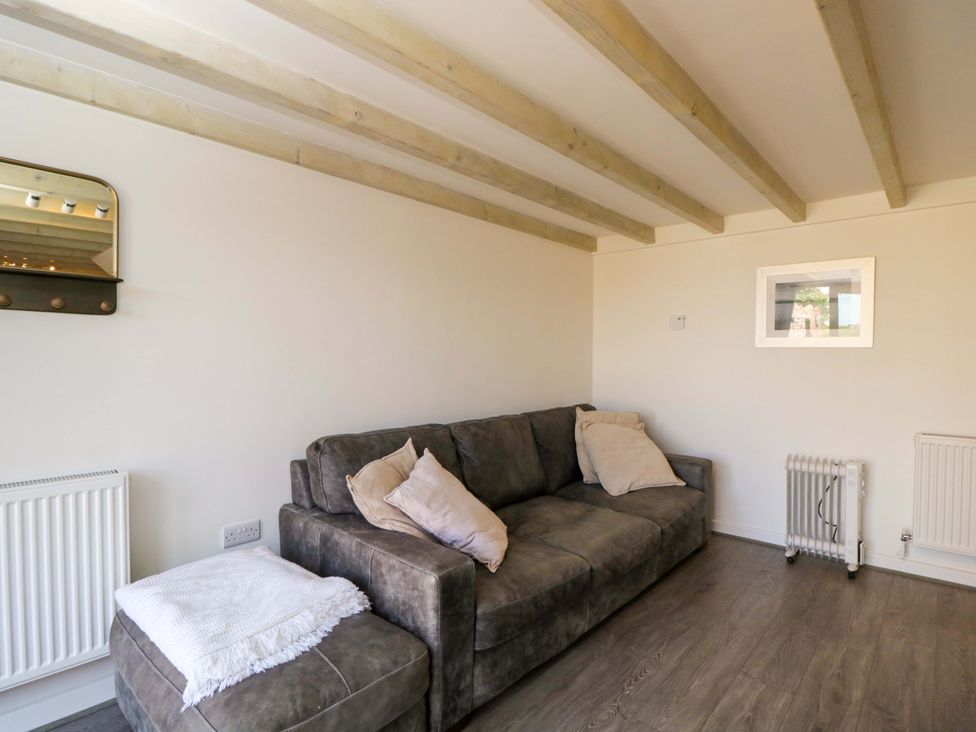 A living room with a sofa and mirror at Barn Cottage in Frome