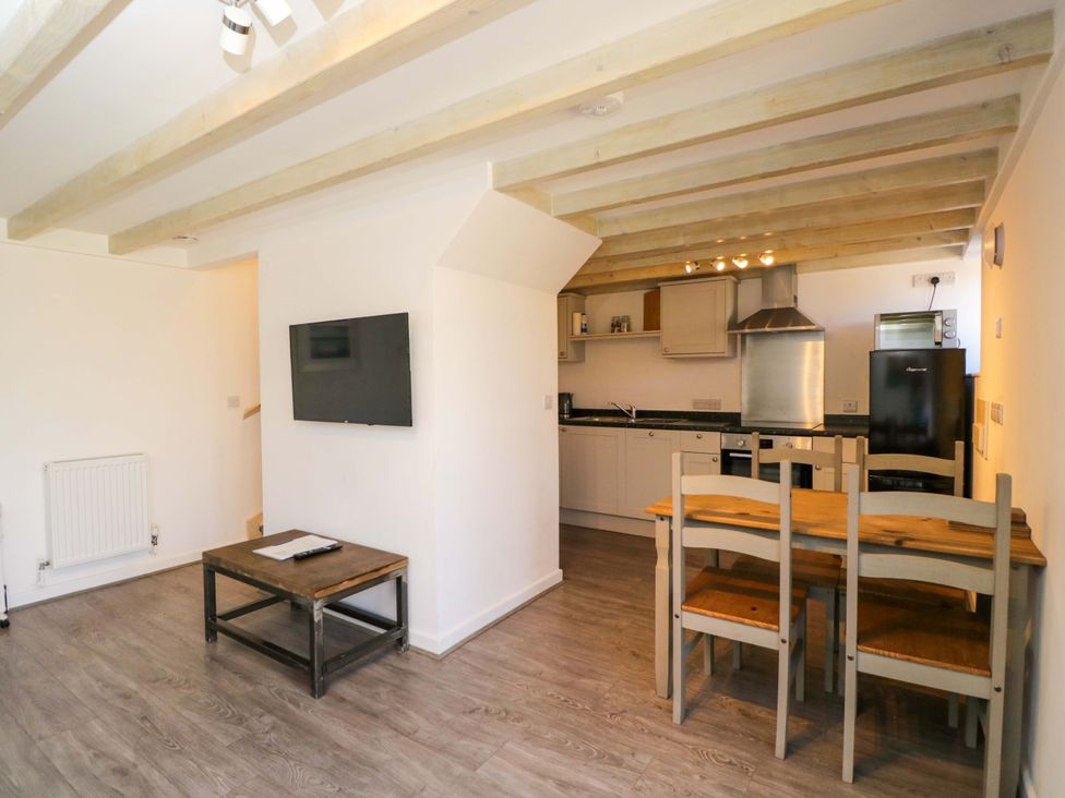 A kitchen with dining table and television at Barn Cottage in Frome