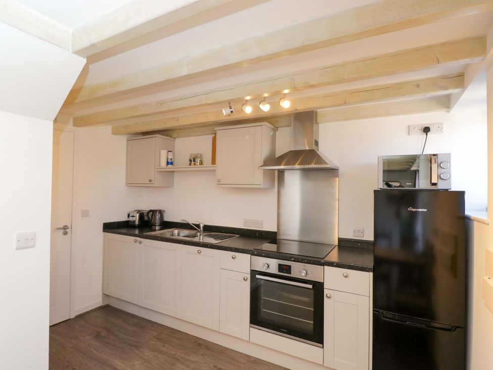 A kitchen with a stove, sink and refrigerator at Barn Cottage Frome
