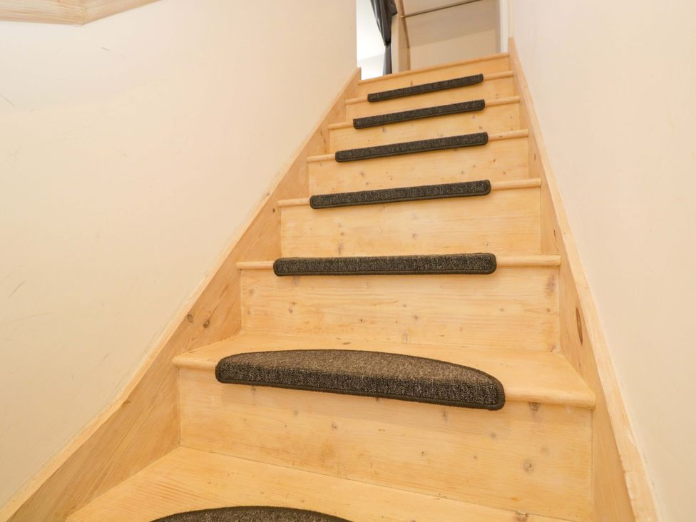 A staircase with wooden steps and carpet treads at Barn Cottage in Frome