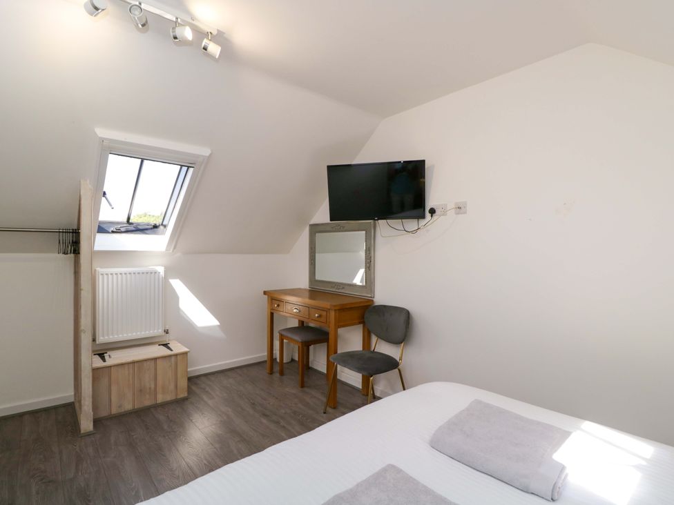 A bedroom with a bed, desk, mirror and television at Barn Cottage in Frome
