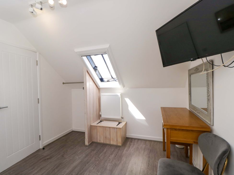 An attic with a skylight, radiator, table, and tv at Barn Cottage in Frome
