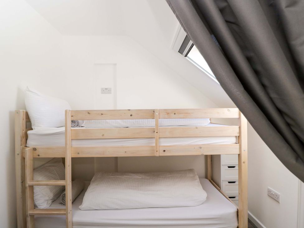 A bunk bed with bedding and a window in a small bedroom at Barn Cottage Frome