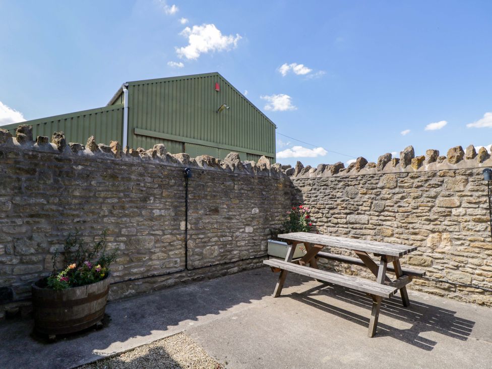 An outdoor area with a picnic table and stone walls at Barn Cottage Frome