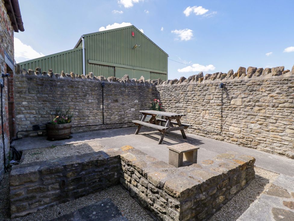 An outdoor area with a picnic table and stone walls at Barn Cottage in Frome