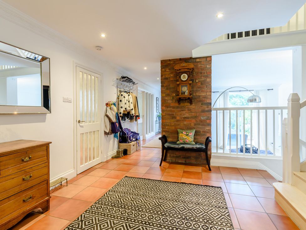 A hallway with a mirror, coat rack, and a clock at Forest Getaway in 