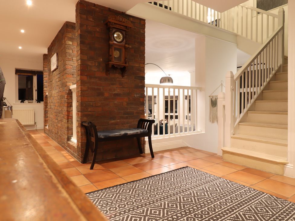A hallway with a clock, a bench, and a staircase at Forest Getaway