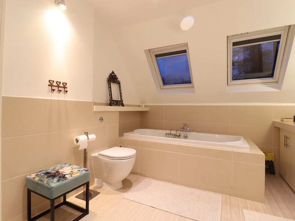 A bathroom with a bathtub, a toilet, and a mirror at Forest Getaway