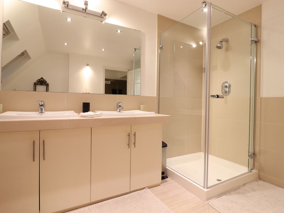 A bathroom with double sinks, mirror, and shower at Forest Getaway