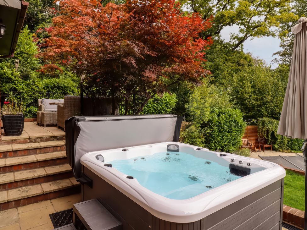A hot tub on a patio surrounded by greenery at Forest Getaway