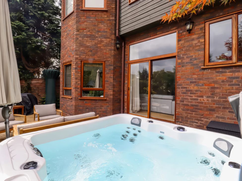 An outdoor patio with a hot tub and seating at Forest Getaway