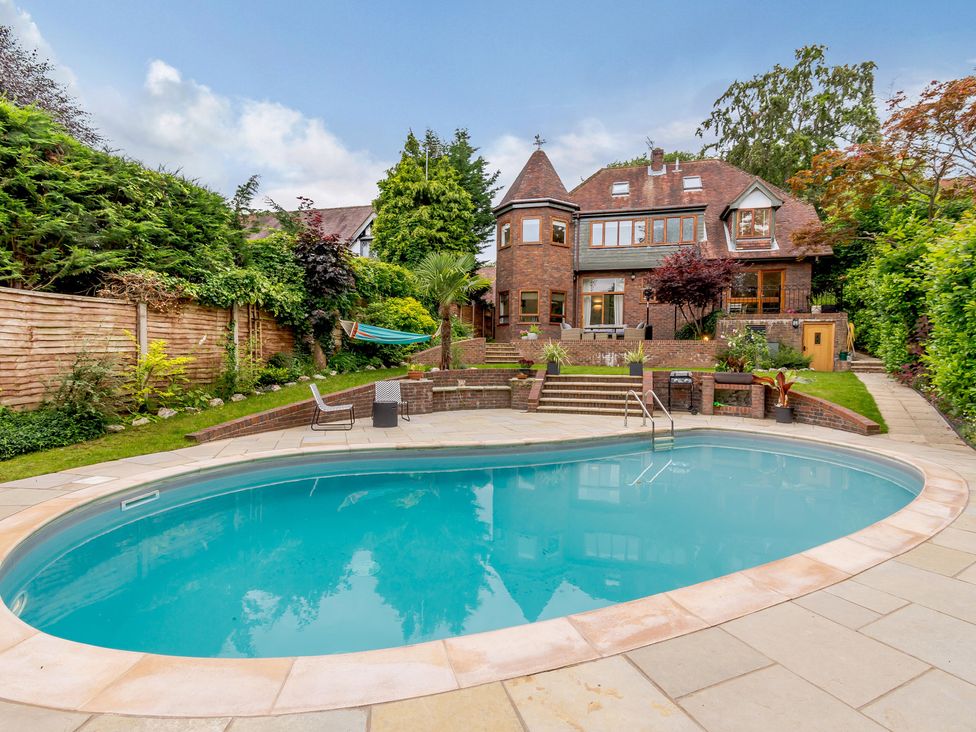 A garden with a swimming pool and a house in the background at Forest Getaway