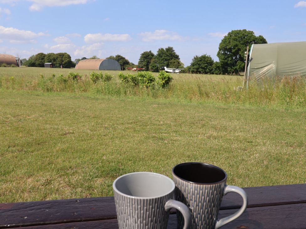 Mugs on a table overlooking a field and buildings at Robin in Monewden near Otley, Suffolk