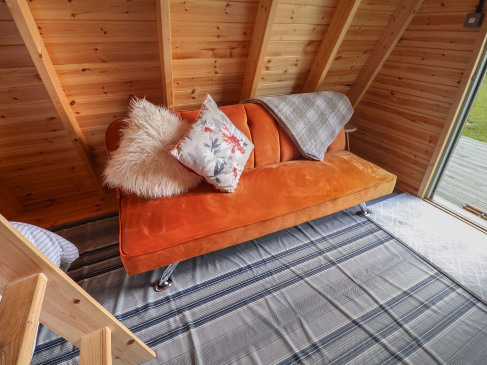 A snug room with an orange sofa and a pillow at Robin in Monewden near Otley, Suffolk