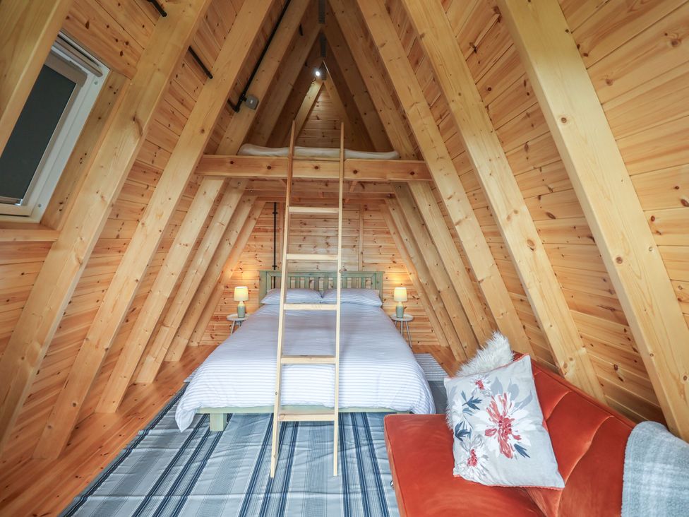 A bedroom with a bed, sofa, and ladder at Robin in Monewden near Otley, Suffolk