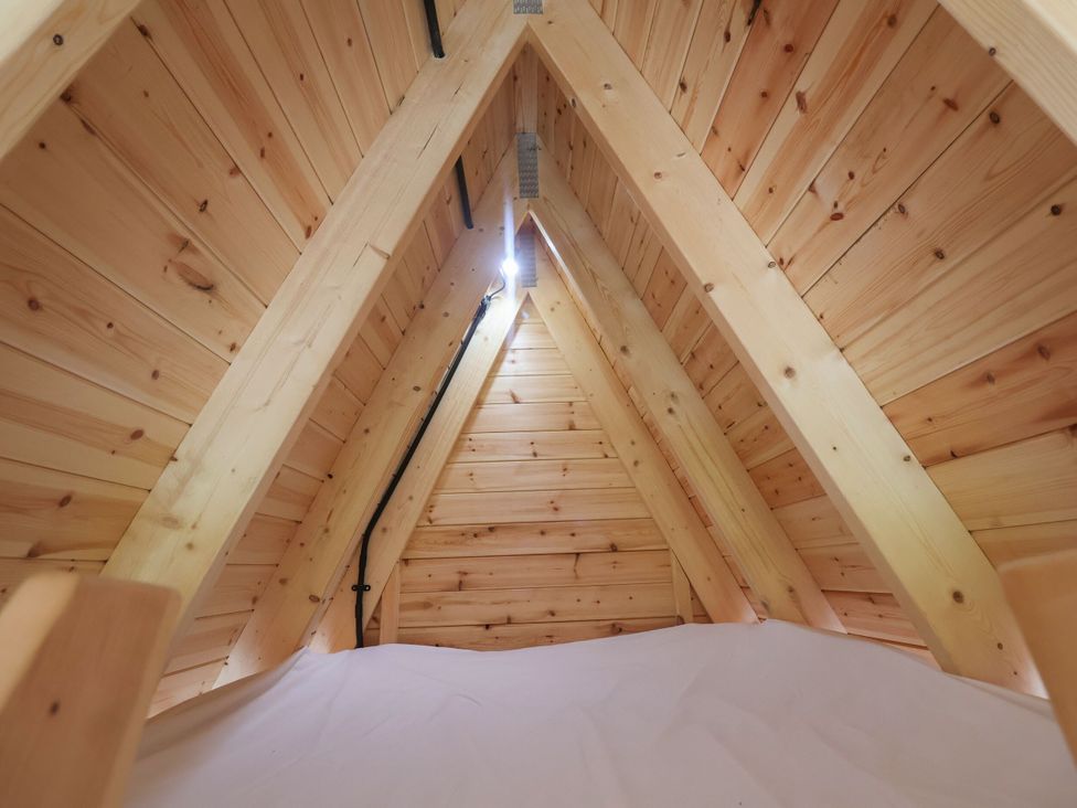 A loft space with wooden beams and white bedding at Robin in Monewden near Otley, Suffolk