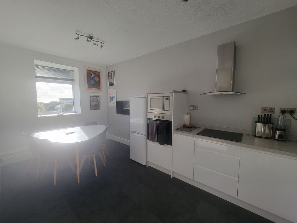 A kitchen with a dining table and chairs at Plas Darien no 28 Trearddur Bay