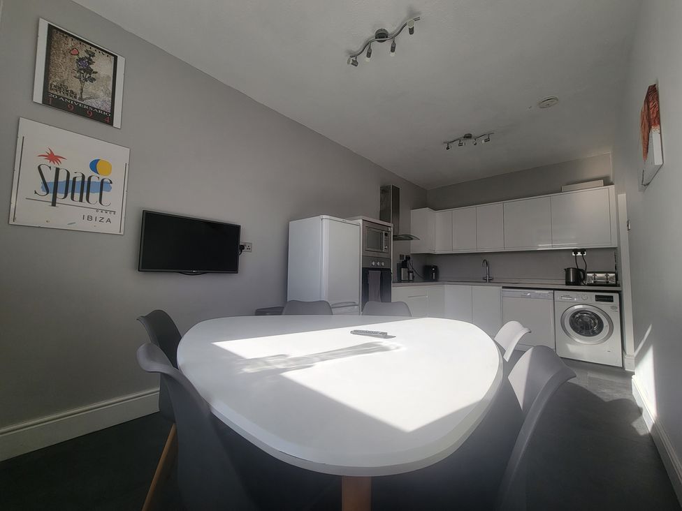 A kitchen with appliances and a dining table at Plas Darien no 28 Trearddur Bay