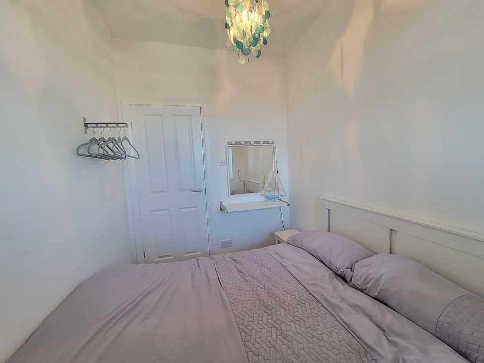 A bedroom with a bed and mirror at Plas Darien no 28 Trearddur Bay