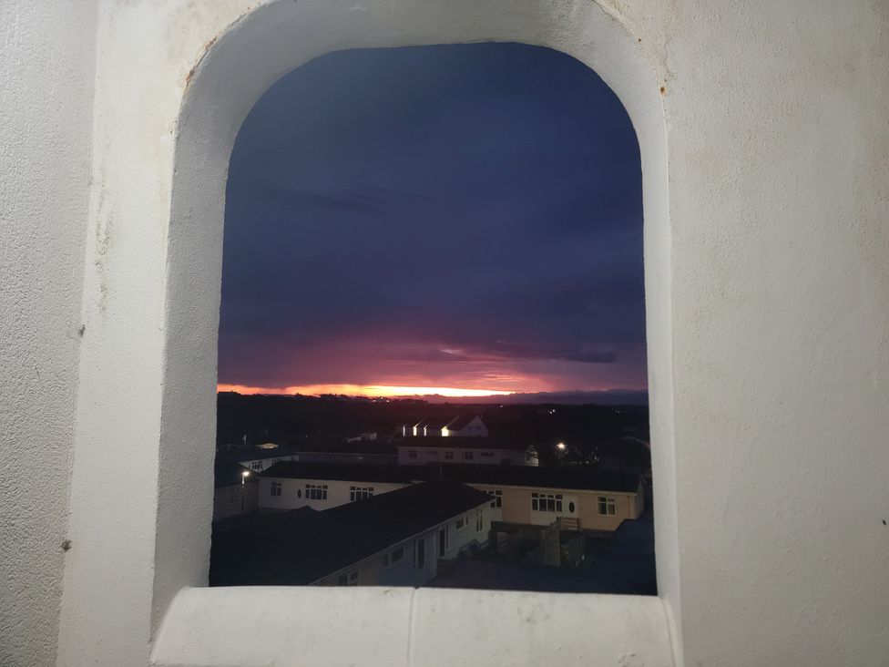 A view of a sunset through a window at Plas Darien no 28 Trearddur Bay