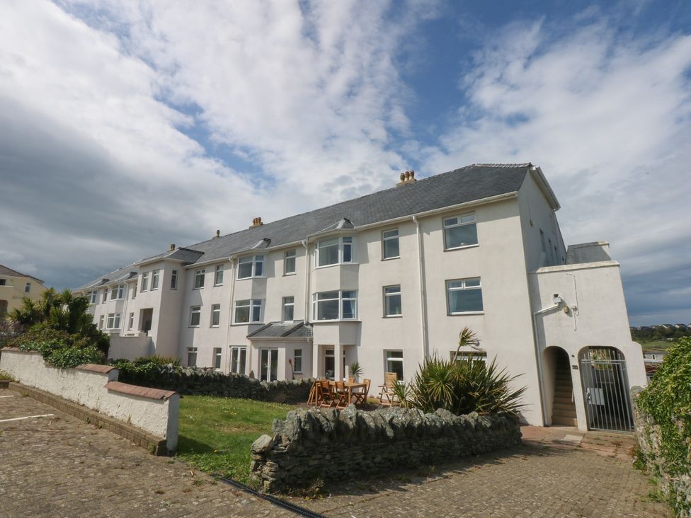 A building with multiple windows and a garden area at Cwtch y Môr in Trearddur Bay