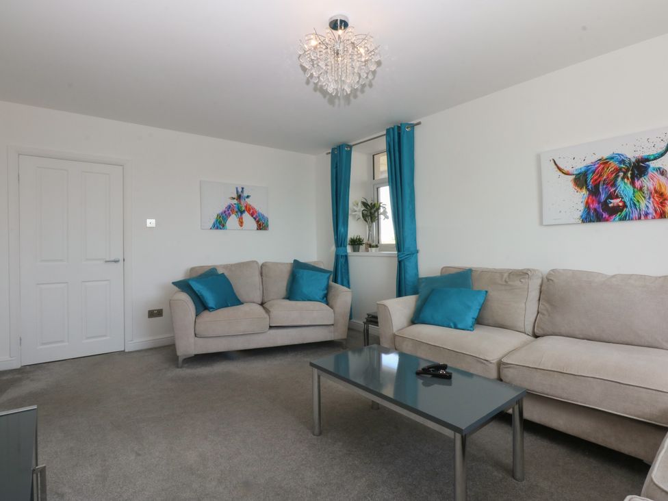 A living room with sofas and a table at Cwtch y Môr in Trearddur Bay