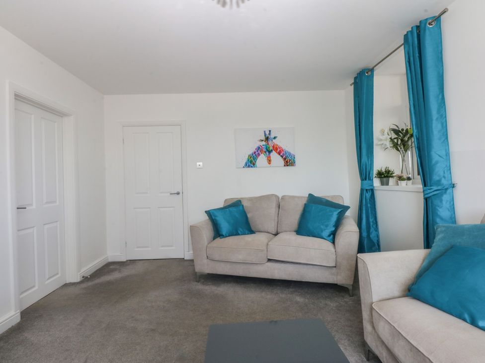 A living room with a sofa and artwork at Cwtch y Môr in Trearddur Bay
