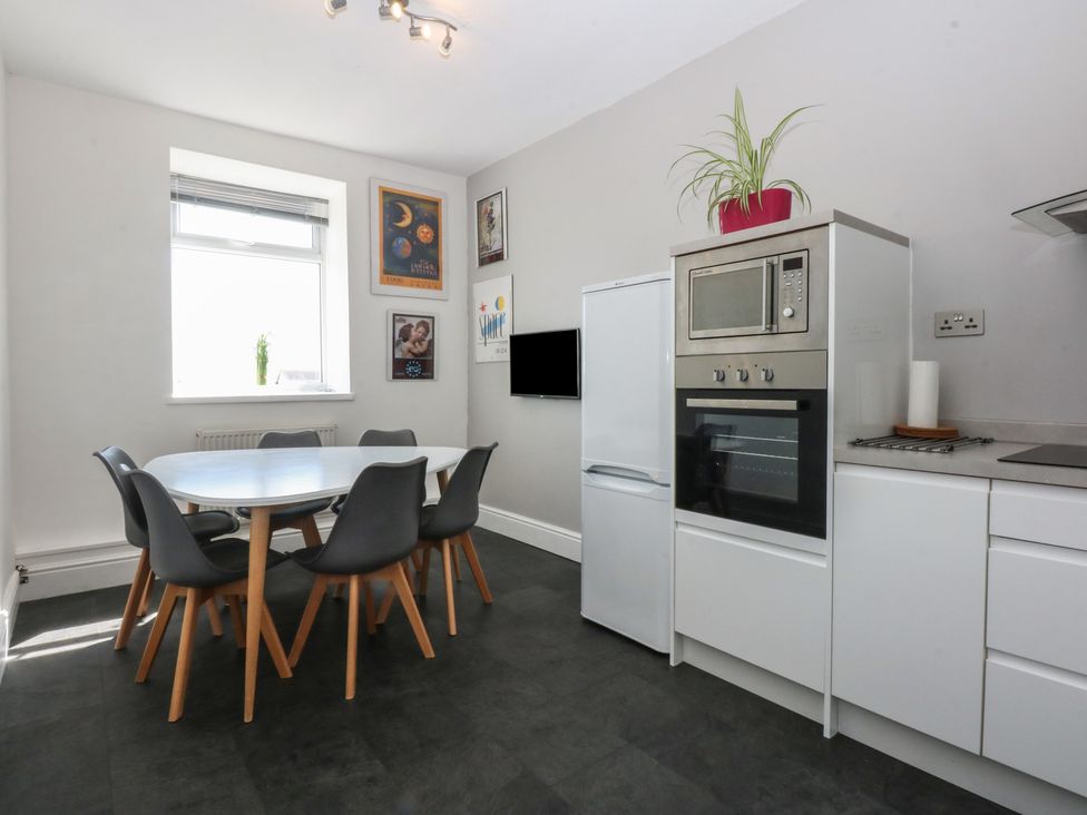 A kitchen with a table and chairs at Cwtch y Môr in Trearddur Bay