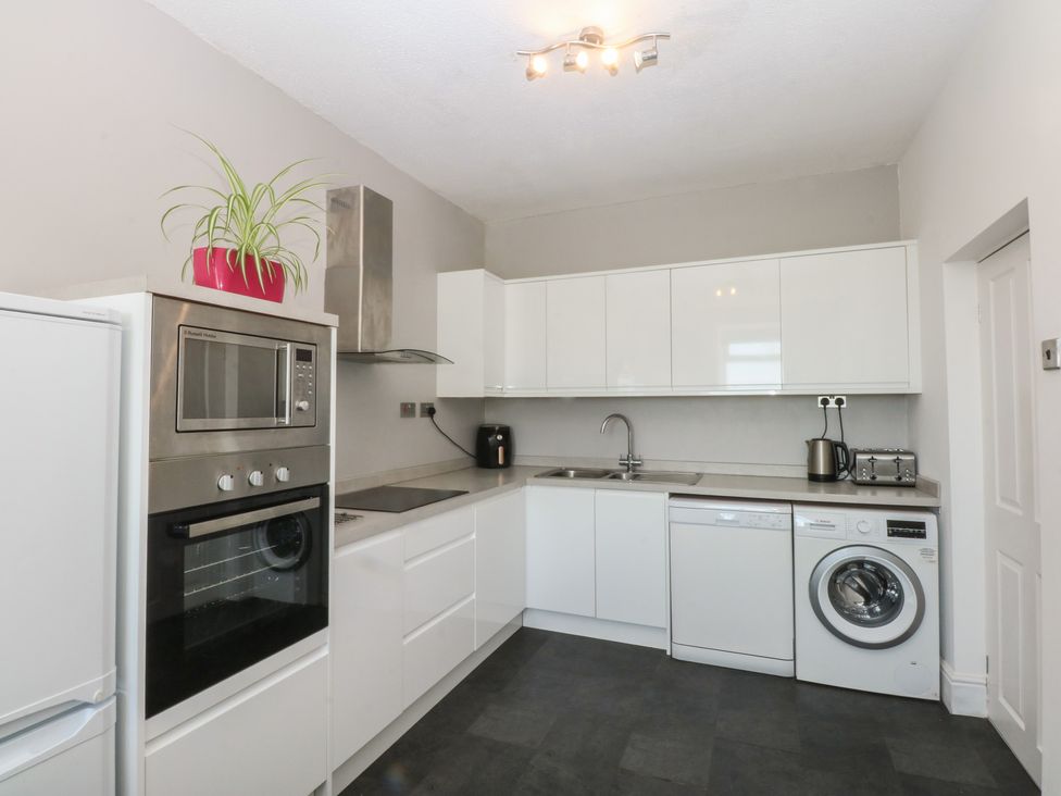 A kitchen with appliances and cabinets at Cwtch y Môr in Trearddur Bay