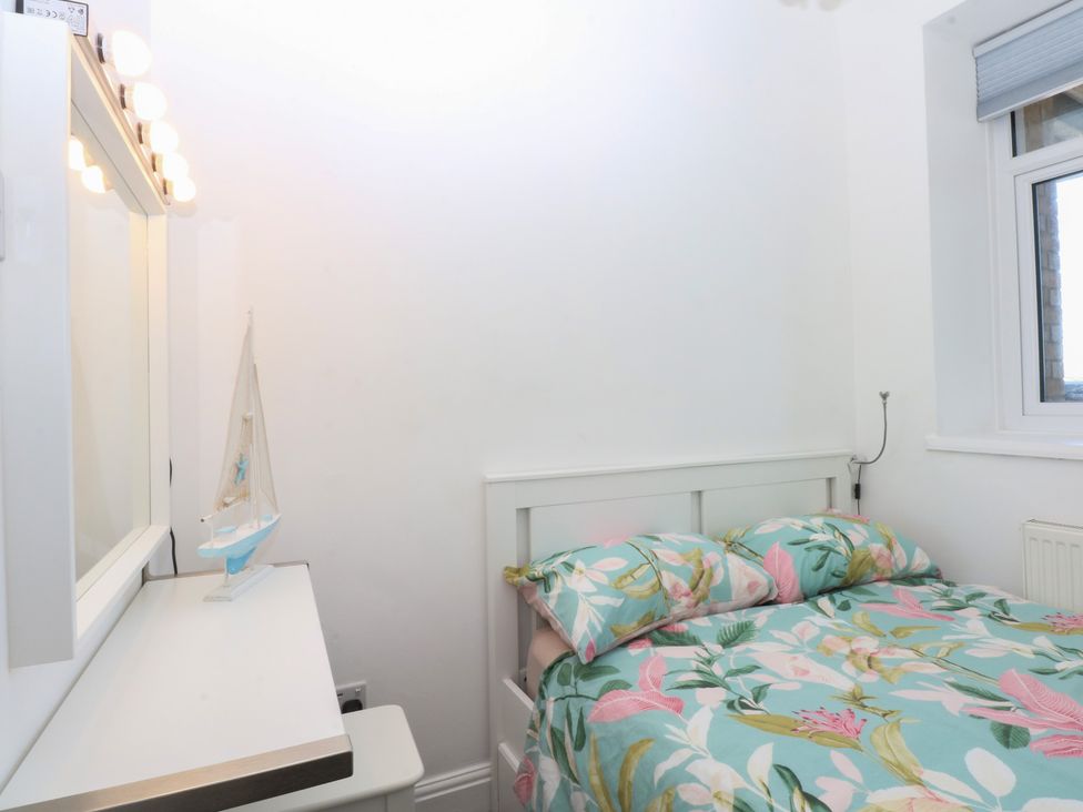 A bedroom with a bed and a vanity at Cwtch y Môr in Trearddur Bay