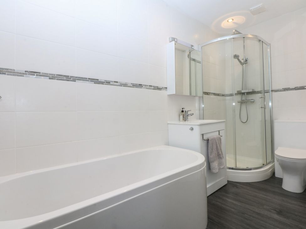 A bathroom with a bathtub, shower, toilet, and sink at Cwtch y Môr in Trearddur Bay