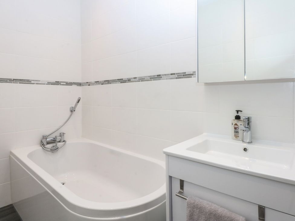 A bathroom with a bathtub and sink at Cwtch y Môr in Trearddur Bay
