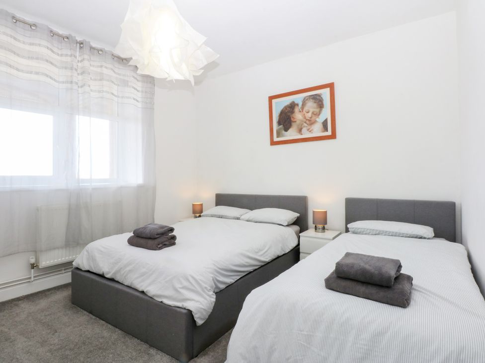A bedroom with two beds and a window at Cwtch y Môr in Trearddur Bay