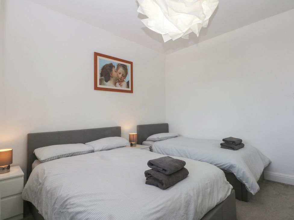 A bedroom with two beds and a picture on the wall at Cwtch y Môr in Trearddur Bay