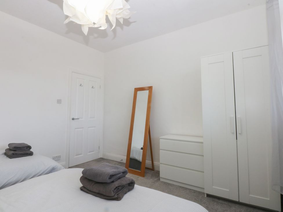 A bedroom with two beds and a wardrobe at Cwtch y Môr in Trearddur Bay