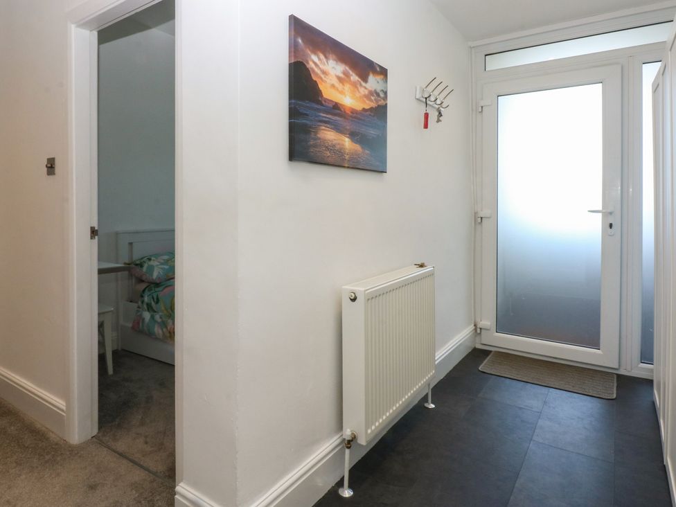 A hallway with a door and radiator at Cwtch y Môr in Trearddur Bay
