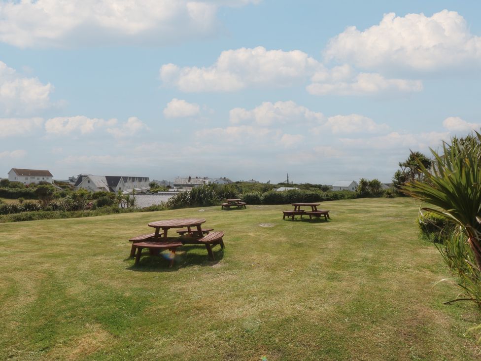 A garden with picnic tables and grass at Cwtch y Môr in Trearddur Bay