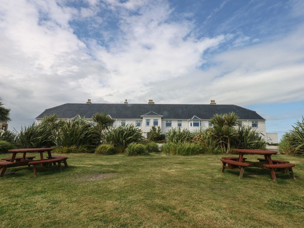 A building with picnic tables and grass at Cwtch y Môr in Trearddur Bay